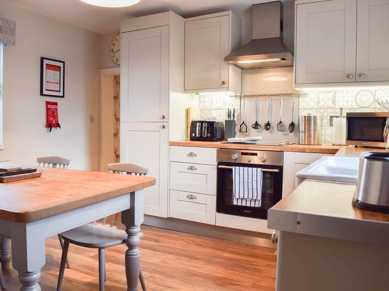 Modern kitchen with white cabinetry, wooden island, stainless steel appliances and dining area