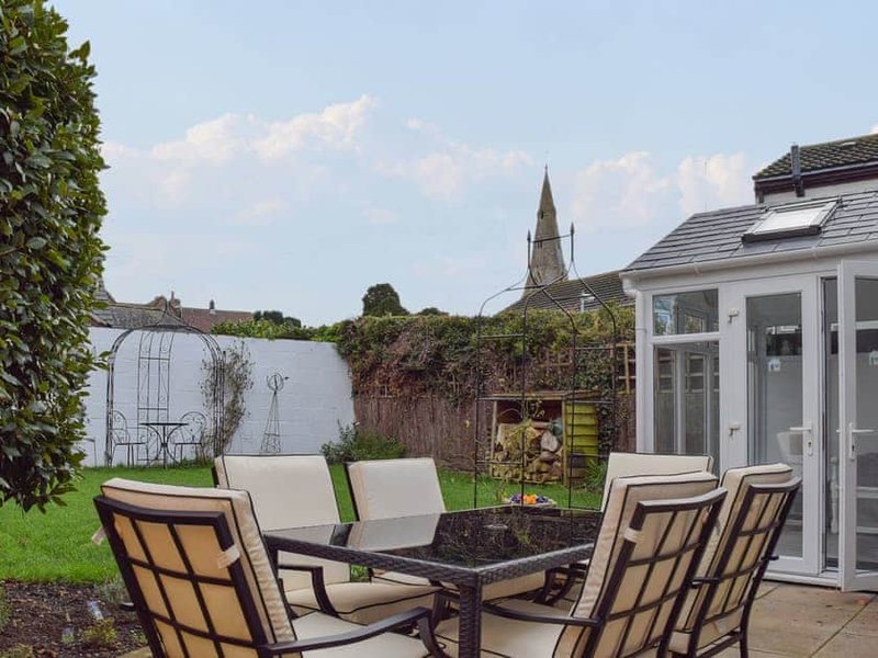 Outdoor patio with garden furniture, fire pit, and countryside views beyond fence