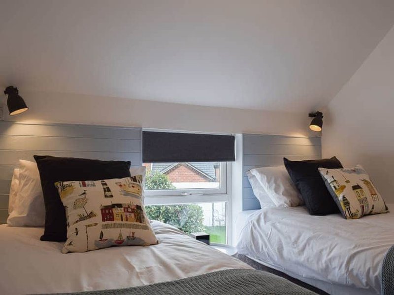 Twin bedroom with white bedding, black pillows, patterned cushions and window shutters