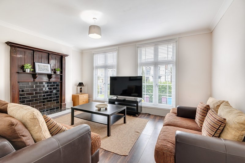 Bright living room with two brown leather sofas, fireplace, TV, and large windows
