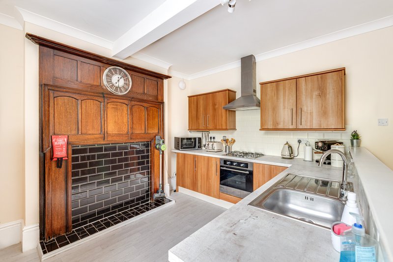 Modern kitchen with wooden cabinets, stainless steel sink, black brick fireplace and clock