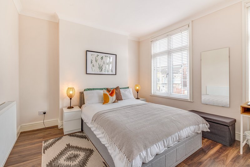 Bright bedroom with double bed, wooden floor, shuttered window and bedside lamps