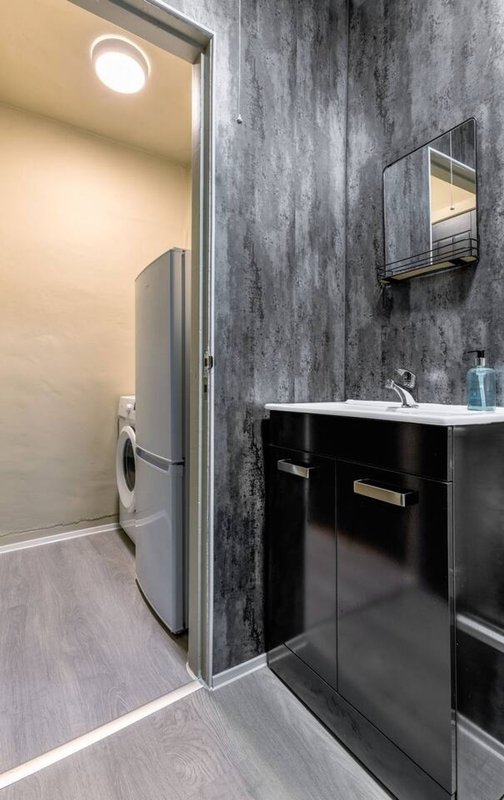 Modern bathroom with black vanity, sink, mirror, and laundry area with washing machine