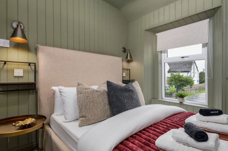Modern bedroom with upholstered headboard, white bedding, decorative pillows and pendant lighting