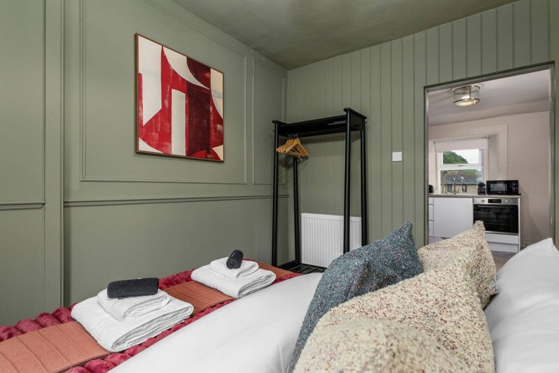 Modern bedroom with double bed, red and white bedding, geometric wall art, and black metal frame