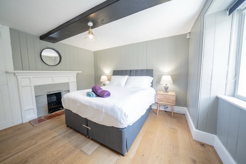 Bright bedroom with double bed, fireplace, wooden floor and bedside lamps