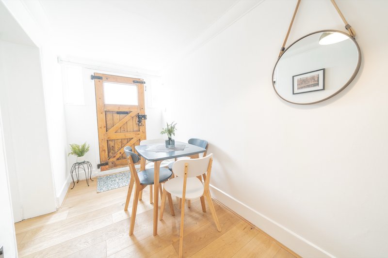 Bright dining area with round table, wooden chairs, mirror, and potted plants