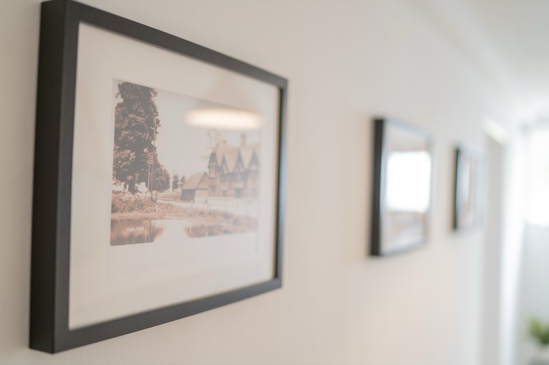 Hallway with framed architectural print on white wall and blurred doorway