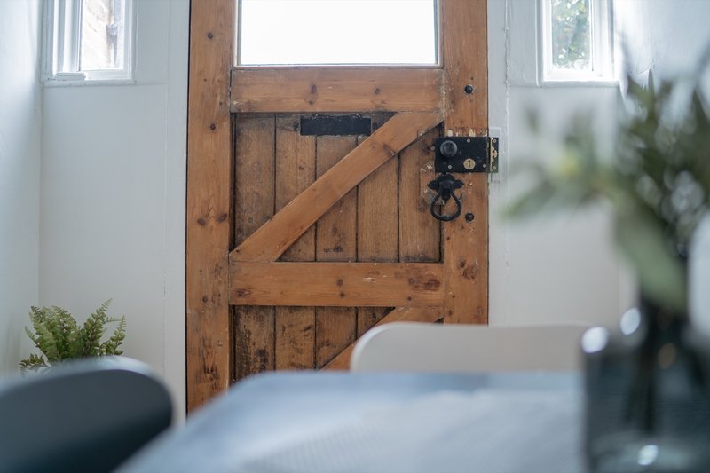 Bedroom interior with wooden barn door, white walls, and potted plant on windowsill