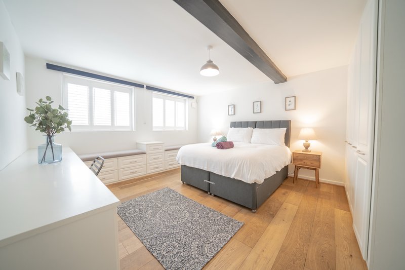 Bright bedroom with double bed, wooden floor, window seating area and pendant lighting