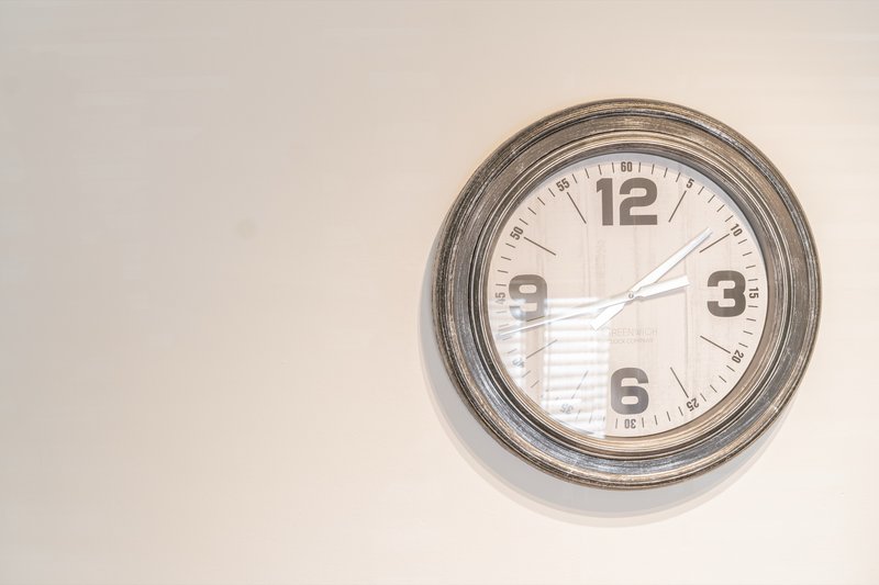 Wall-mounted round clock with gray metal frame on white wall