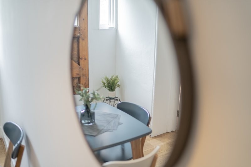 Dining area with round mirror reflection, table, chairs, and fresh flowers in vase