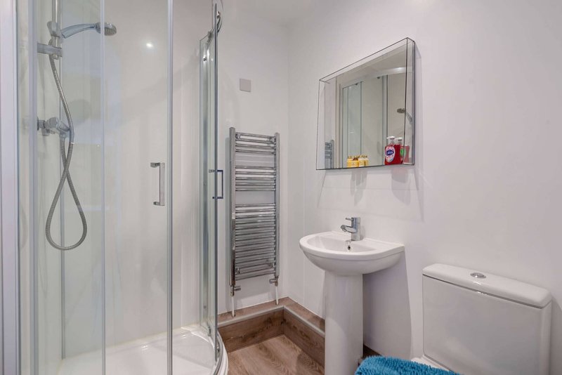 Modern bathroom with walk-in shower, pedestal sink, heated towel rail and mirror cabinet