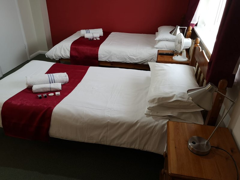 Modern twin bedroom with white bedding, burgundy runners and pillows, wooden nightstands