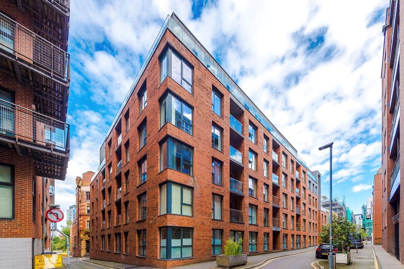 Red brick apartment building exterior with multiple windows and street-level parking