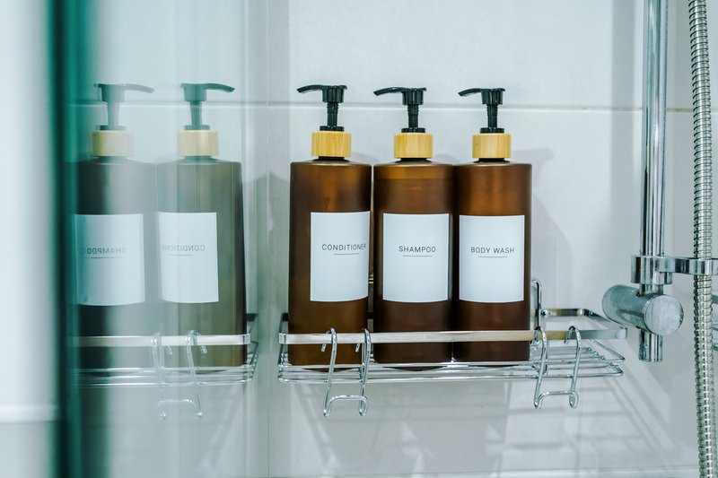 Bathroom shelf with toiletries in pump bottles and glass containers