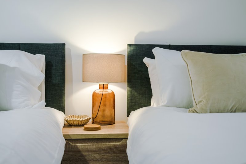 Twin beds with white pillows, green headboards, and bedside lamp between them