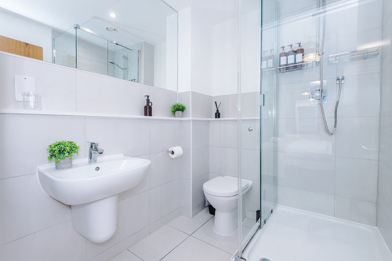 Modern white bathroom with wall-mounted sink, toilet, glass shower enclosure and shelving