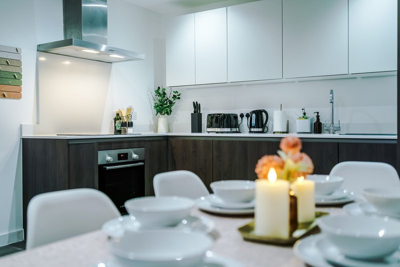 Modern kitchen with dark lower cabinets, white upper cabinets, dining table with place settings and centerpiece