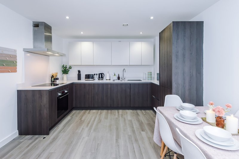 Modern kitchen with dark wood cabinetry, white upper cabinets, and dining table set for two