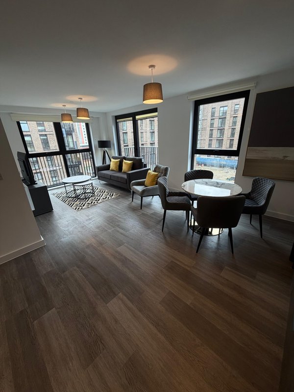 Modern open-plan apartment with dining table, seating area, hardwood floors and pendant lighting