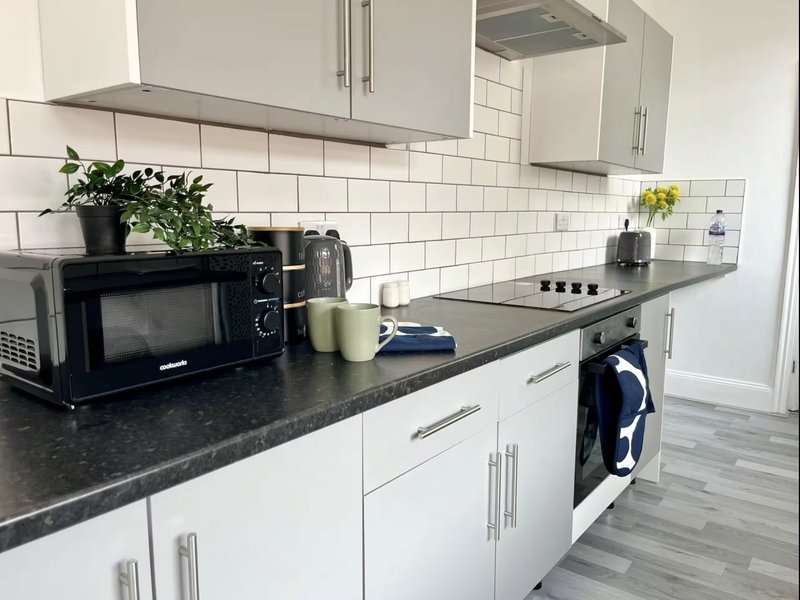 Modern kitchen with white cabinetry, dark countertops, subway tile backsplash, and black appliances