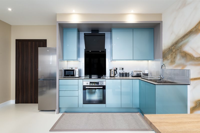 Modern kitchen with light blue cabinetry, stainless steel appliances, and marble backsplash