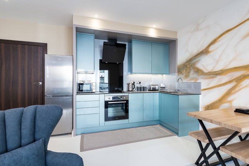 Modern kitchen with light blue cabinetry, stainless steel appliances, marble backsplash and dining table