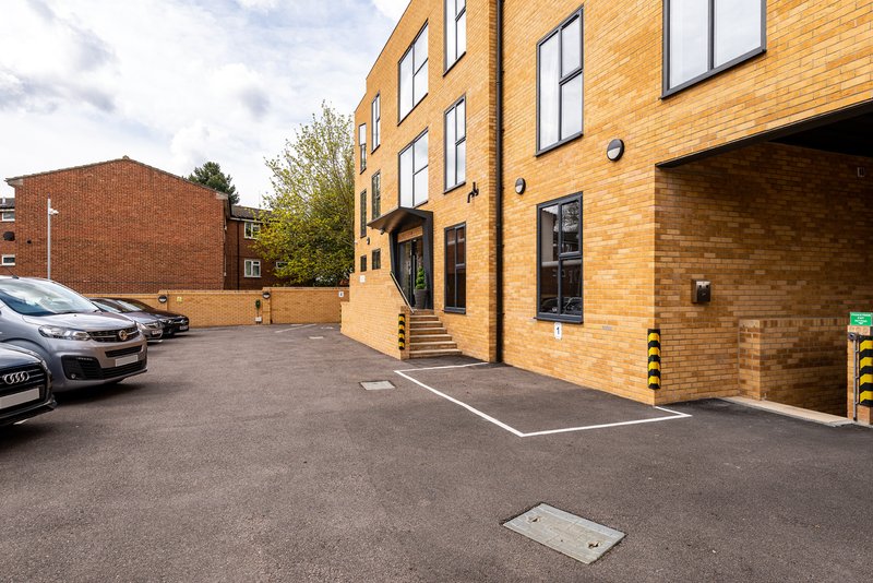 Modern brick apartment building with parking area, parked cars and entrance