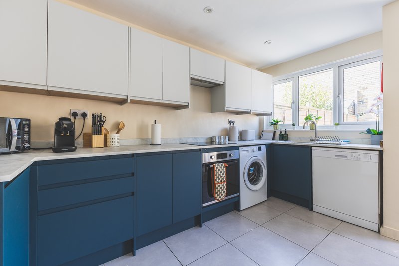Modern kitchen with blue cabinetry, stainless steel appliances, and light wood accents