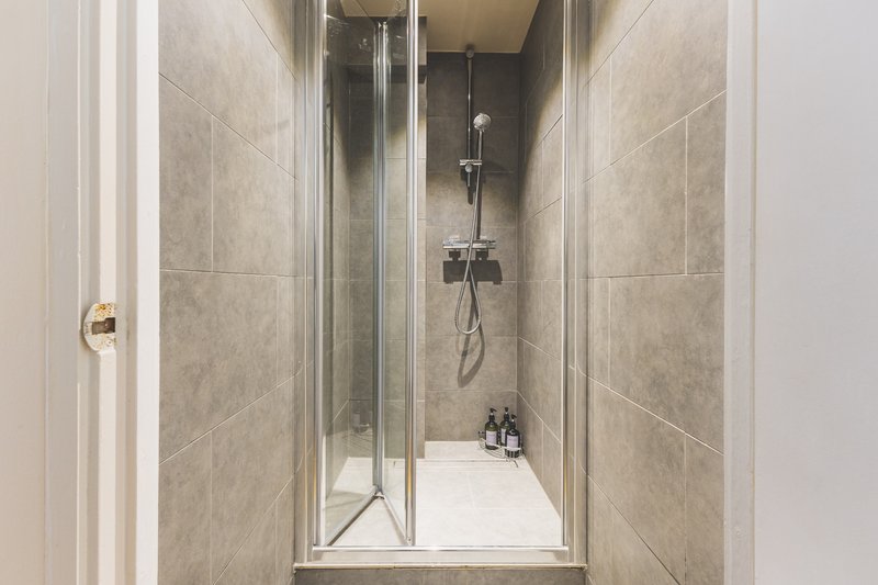 Modern shower enclosure with glass doors, gray tile walls, and chrome fixtures