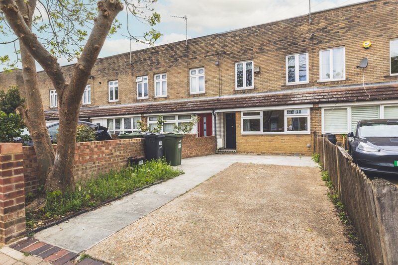 Brick terraced house with driveway, front garden and parked car visible