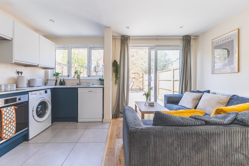 Open-plan kitchen and living room with modern appliances, sofa, and glass doors to garden