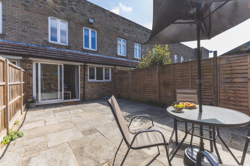 Brick townhouse with paved patio, dining table, chairs and umbrella in enclosed garden