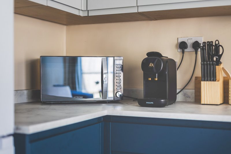 Modern kitchen counter with microwave, coffee machine, TV, and utensil holder