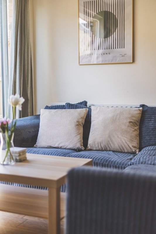 Modern living room with blue striped sofa, cushions, wooden coffee table and framed wall art