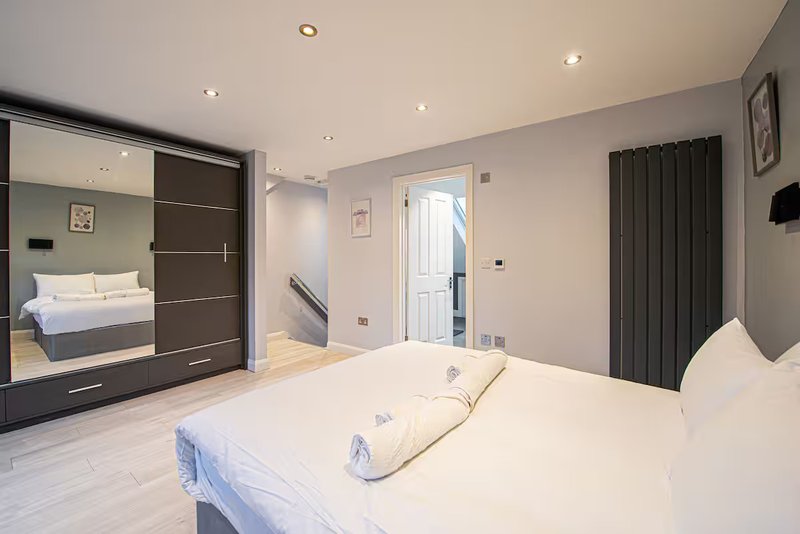 Modern bedroom with double bed, mirrored wardrobe, radiator and ensuite door