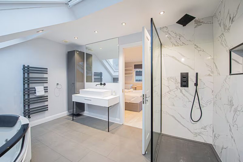 Modern bathroom with walk-in shower, white vanity sink, heated towel rail and marble tiling