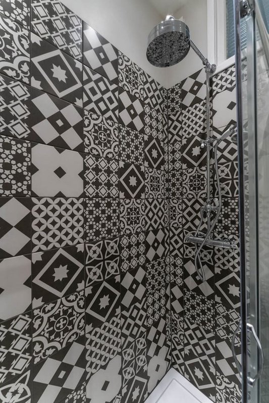 Shower enclosure with black and white geometric patterned tiles and chrome fixtures