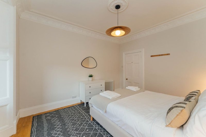 Bright bedroom with two single beds, wooden floor, white walls and pendant light fixture