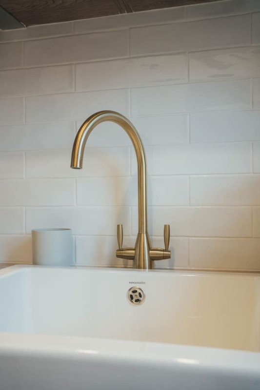 Modern bathroom sink with brass faucet and white subway tile backsplash