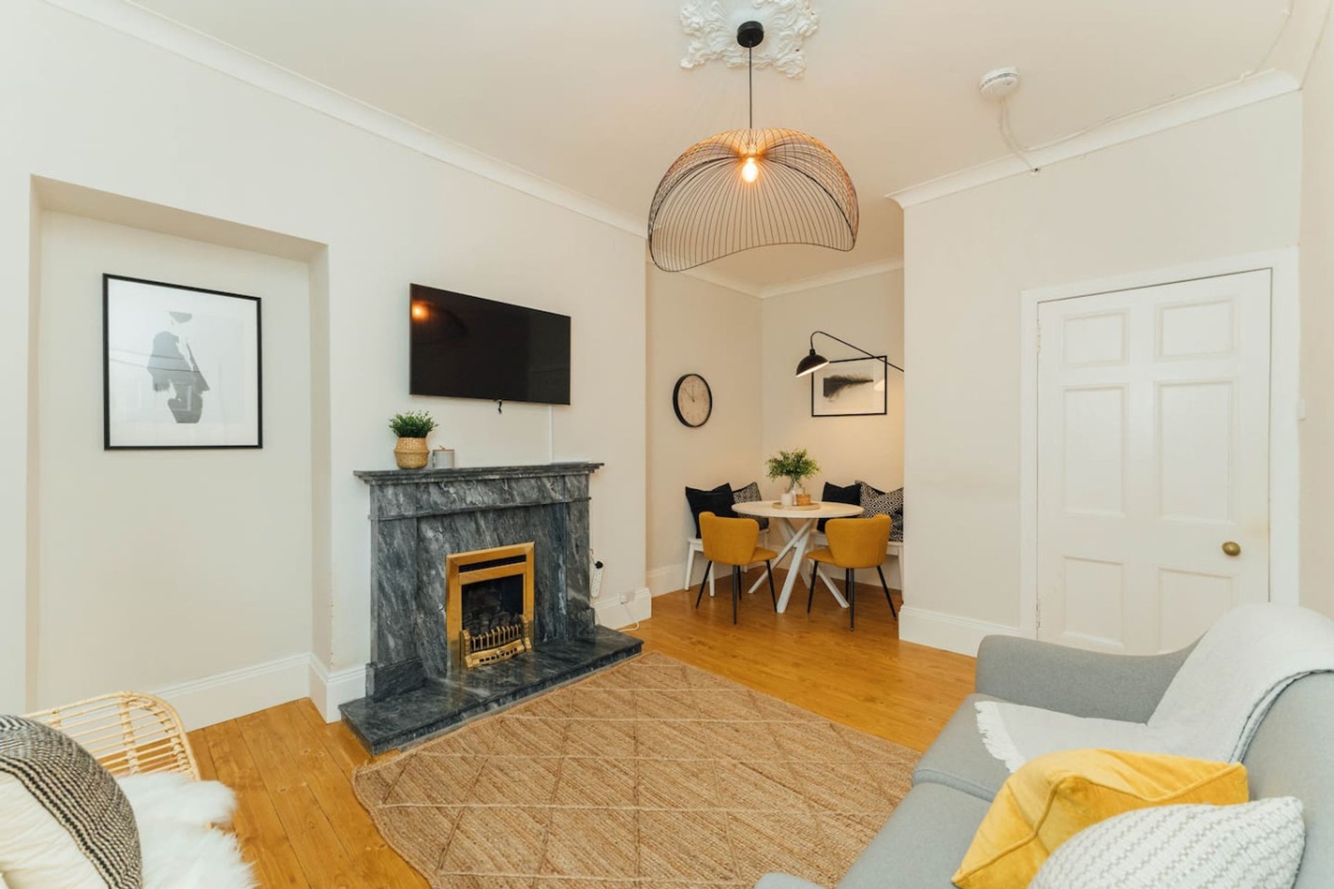 Living room with fireplace, TV, dining table, and seating area with wooden flooring