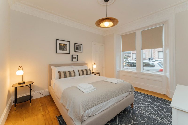 Bright bedroom with double bed, wooden floor, pendant light, and street-view windows