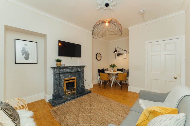 Bright living room with fireplace, dining area, TV, wooden floors and contemporary furnishings