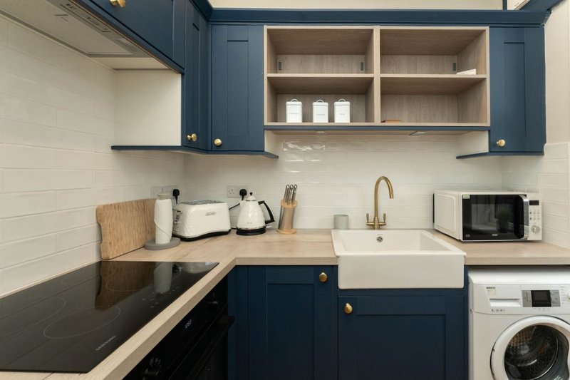 Modern kitchen with navy cabinets, white subway tile, wooden countertop, sink and appliances