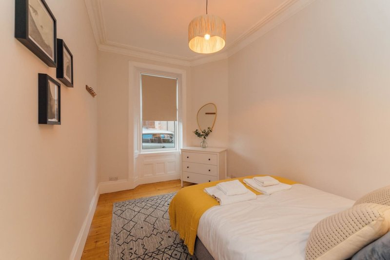 Bright bedroom with double bed, wooden floor, pendant light and wall-mounted shelves