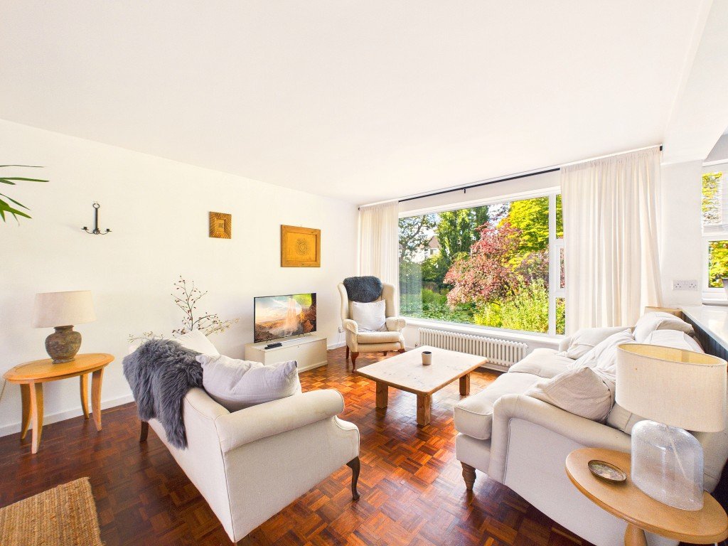 Bright living room with cream sofas, wooden coffee table, and garden view through large windows