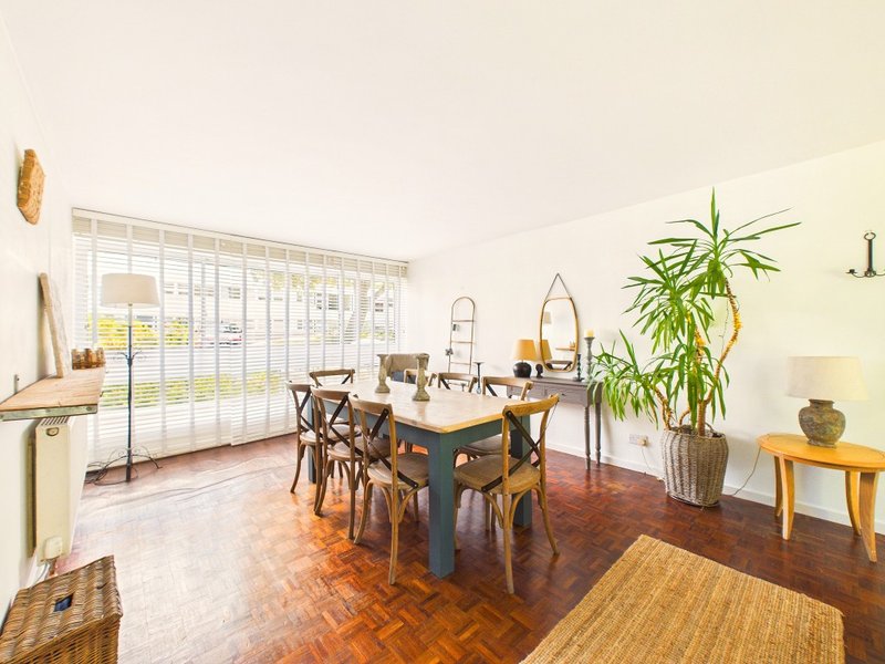 Dining room with wooden table, chairs, potted plant, and sliding glass doors to garden