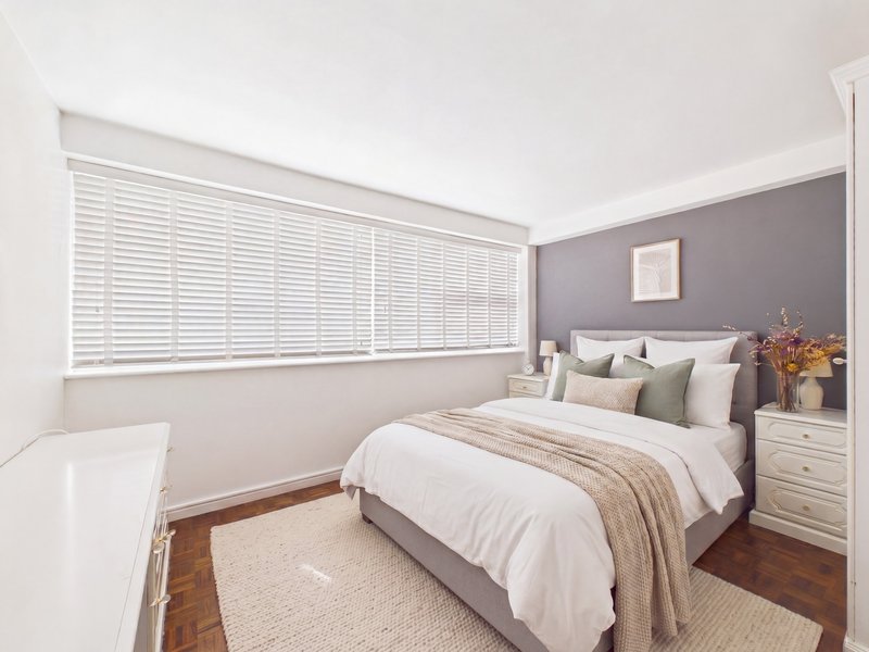 Modern bedroom with double bed, grey accent wall, white shutters and wooden flooring