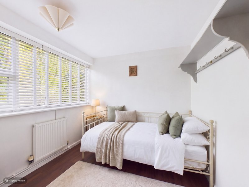 Bright bedroom with single bed, white shutters, wooden floor and cream bedding